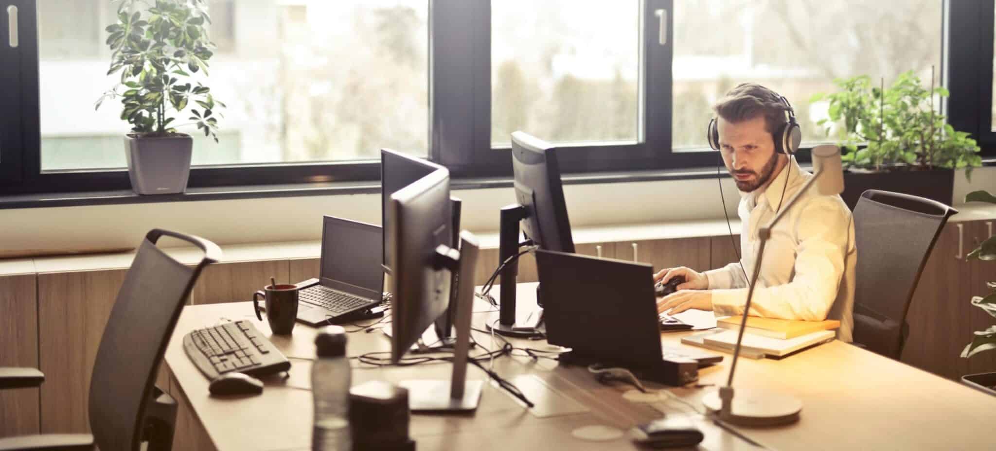 Man With Headphones Facing Computer Monitor